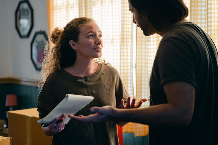Image of a worried looking woman holding a notepad and talking with a man in their home to accompany justice gap text.
